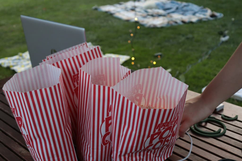 Popcorn bags on a patio table before an outdoor movie night on the lawn
